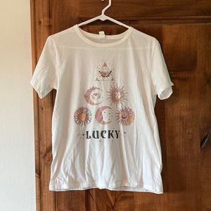 White short sleeve shirt with astrological pictures and “LUCKY” on it